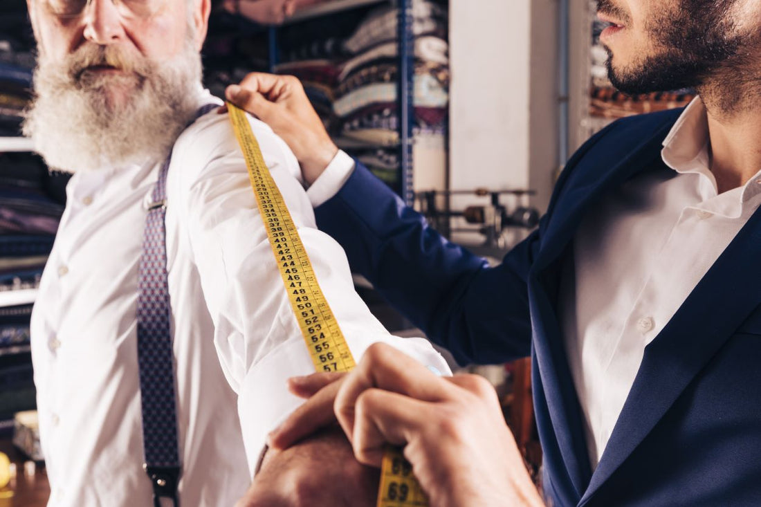 Tailor measuring client’s arm for a custom suit fitting in a bespoke menswear shop”